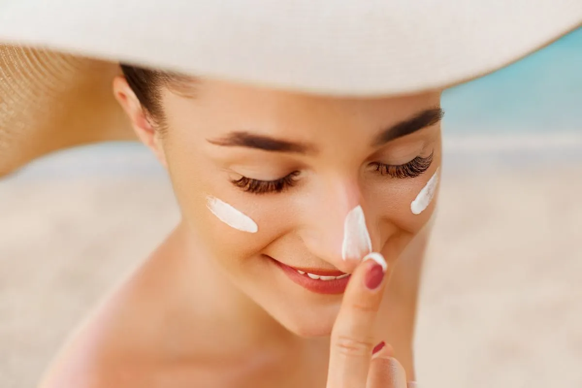 woman applies cream to face